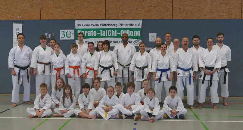 Große Karategruppe mit Kindern und Erwachsenen in einer Sporthalle